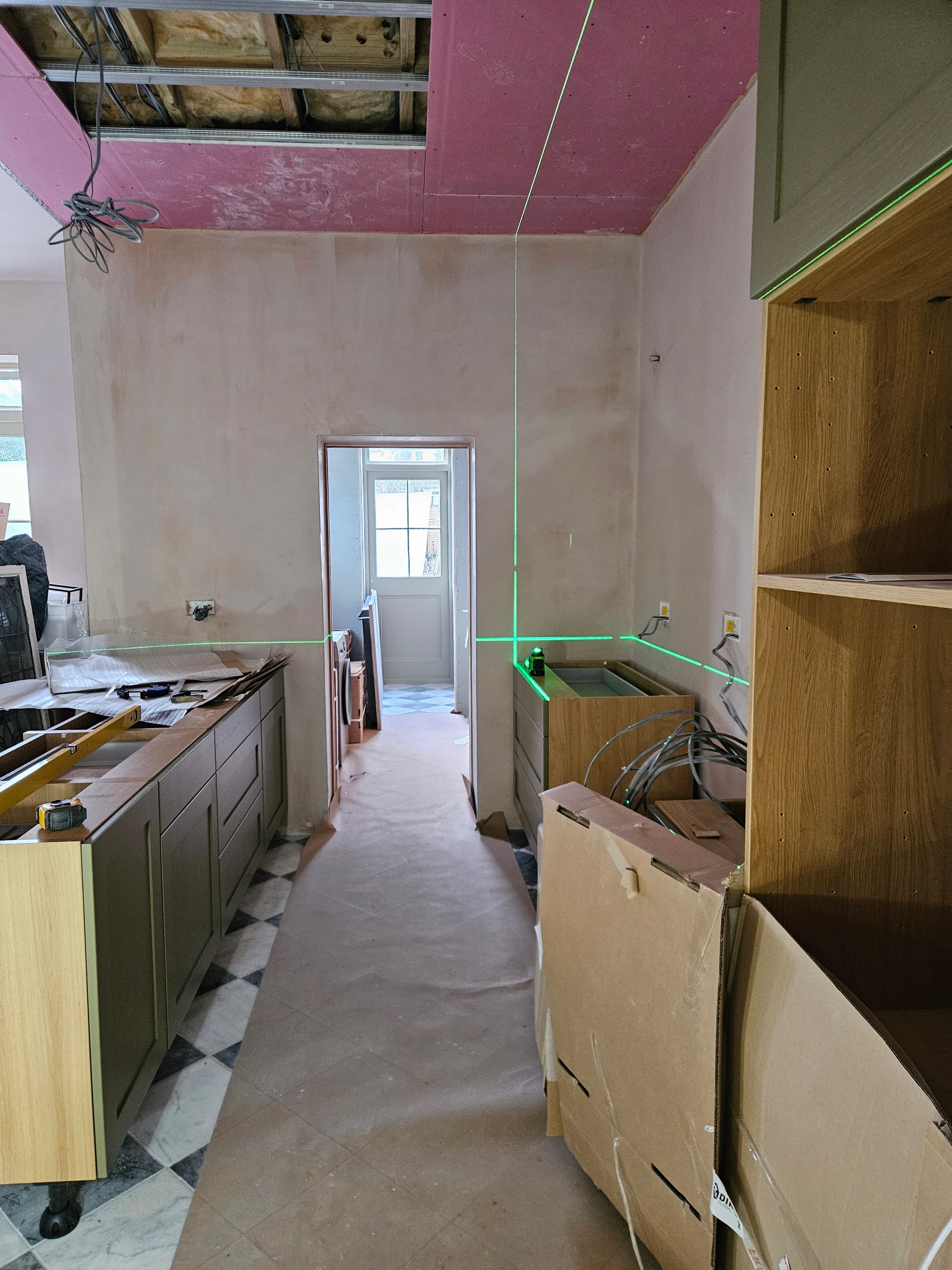 Kitchen installation beginning, cabinets going in with laser level